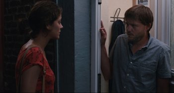 Movie still from “Two Days, One Night” (2014), directed by Jean-Pierre Dardenne – A man and a woman standing next to each other in front of a door; Medium shot, Over the shoulder angle