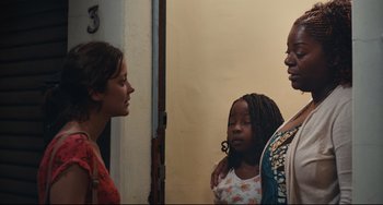 Movie still from “Two Days, One Night” (2014), directed by Jean-Pierre Dardenne – Two women and a girl standing next to each other; Medium shot, Over the shoulder angle