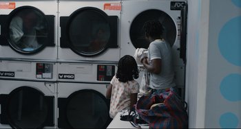 Movie still from “Two Days, One Night” (2014), directed by Jean-Pierre Dardenne – A couple of people that are in a laundry room; Medium shot, High angle