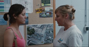 Movie still from “Two Days, One Night” (2014), directed by Jean-Pierre Dardenne – Two women standing in front of a bulletin board; Medium shot, Over the shoulder angle