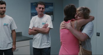 Movie still from “Two Days, One Night” (2014), directed by Jean-Pierre Dardenne – A man standing next to two women in a room; Medium shot, Over the shoulder angle