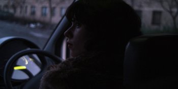 Movie still from “Under the Skin” (2013), directed by Jonathan Glazer – A woman sitting in the driver's seat of a car; Close Up shot, Over the shoulder angle