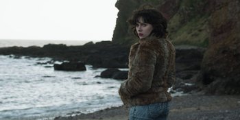 Movie still from “Under the Skin” (2013), directed by Jonathan Glazer – A woman standing on the beach wearing a fur coat; Medium shot, Low angle