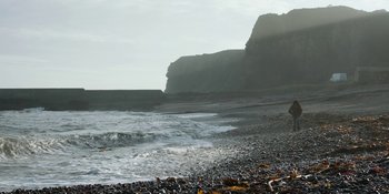 Movie still from “Under the Skin” (2013), directed by Jonathan Glazer – A rocky beach with waves crashing on the shore; Extreme Wide shot, Low angle