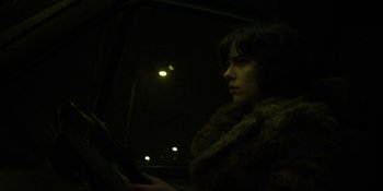 Movie still from “Under the Skin” (2013), directed by Jonathan Glazer – A woman sitting in a car looking out the window at night; Close Up shot, Low angle