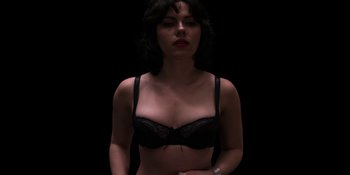 Movie still from “Under the Skin” (2013), directed by Jonathan Glazer – A woman in a black bra is posing for the camera; Medium shot, Overhead angle