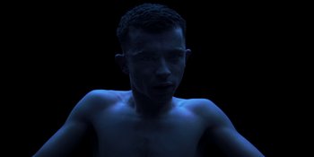 Movie still from “Under the Skin” (2013), directed by Jonathan Glazer – A man with blue light shining on his face; Close Up shot, High angle