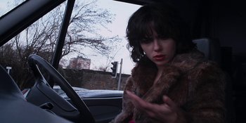 Movie still from “Under the Skin” (2013), directed by Jonathan Glazer – A woman in a fur coat sitting in the driver's seat of a car; Close Up shot, Low angle