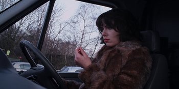 Movie still from “Under the Skin” (2013), directed by Jonathan Glazer – A woman sitting in the drivers seat of a car; Close Up shot, Low angle