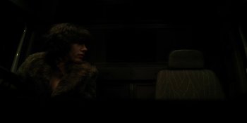 Movie still from “Under the Skin” (2013), directed by Jonathan Glazer – A person sitting on a bus in the middle of the night; Medium shot, Over the shoulder angle