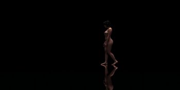 Movie still from “Under the Skin” (2013), directed by Jonathan Glazer – A woman standing in the middle of a dark room; Extreme Wide shot, Overhead angle