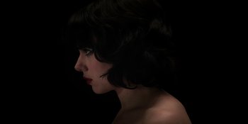 Movie still from “Under the Skin” (2013), directed by Jonathan Glazer – A person wearing a black wig; Close Up shot, Low angle
