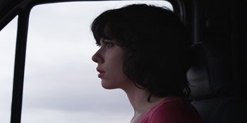 Movie still from “Under the Skin” (2013), directed by Jonathan Glazer – A young woman looking out the window of a vehicle; Close Up shot, Low angle