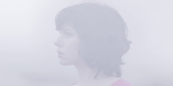 Movie still from “Under the Skin” (2013), directed by Jonathan Glazer – A woman in a pink shirt is in the fog; Close Up shot, Overhead angle