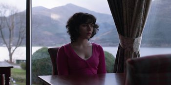 Movie still from “Under the Skin” (2013), directed by Jonathan Glazer – A woman sitting at a table looking out a window; Medium shot, Over the shoulder angle