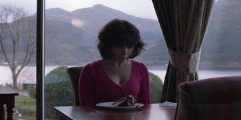Movie still from “Under the Skin” (2013), directed by Jonathan Glazer – A woman sitting at a table with a piece of cake; Medium shot, High angle