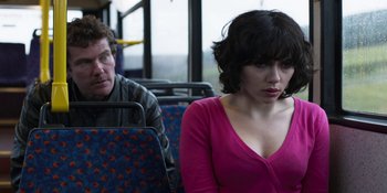 Movie still from “Under the Skin” (2013), directed by Jonathan Glazer – A man and a woman sitting on a public bus; Medium shot, Over the shoulder angle