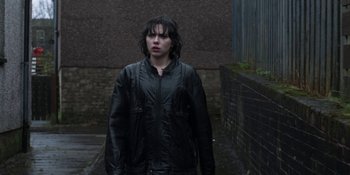 Movie still from “Under the Skin” (2013), directed by Jonathan Glazer – A woman standing in the rain wearing a black jacket; Medium shot, Over the shoulder angle