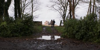 Movie still from “Under the Skin” (2013), directed by Jonathan Glazer – Two people are standing on a dirt road; Wide shot, Low angle