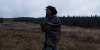 Movie still from “Under the Skin” (2013), directed by Jonathan Glazer – A woman walking through a field with a blanket over her head; Medium shot, Low angle