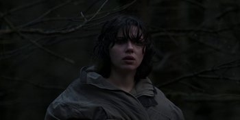 Movie still from “Under the Skin” (2013), directed by Jonathan Glazer – A woman with wet hair standing next to a tree; Medium shot, Low angle