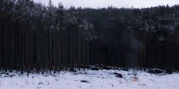 Movie still from “Under the Skin” (2013), directed by Jonathan Glazer – A group of people standing in the middle of a snow covered forest; Extreme Wide shot, Low angle