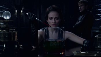 Movie still from “Underworld: Blood Wars” (2016), directed by Anna Foerster – A woman holding a knife in her mouth and holding a glass; Medium shot, Over the shoulder angle