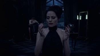 Movie still from “Underworld: Blood Wars” (2016), directed by Anna Foerster – A woman in a black dress smoking a cigarette in front of a mirror; Medium shot, Over the shoulder angle