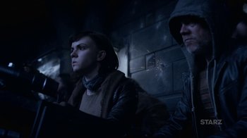 Movie still from “Underworld: Blood Wars” (2016), directed by Anna Foerster – A woman and a man sitting next to each other in front of a brick wall; Medium shot, Over the shoulder angle