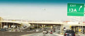 Movie still from “United 93” (2006), directed by Paul Greengrass – An airplane is flying over a busy highway; Extreme Wide shot, Low angle