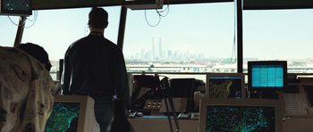 Movie still from “United 93” (2006), directed by Paul Greengrass – A man standing in front of a window with a view of a city; Extreme Wide shot, Over the shoulder angle