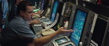 Movie still from “United 93” (2006), directed by Paul Greengrass – A man is working on a computer in a room; Medium shot, High angle