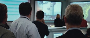 Movie still from “United 93” (2006), directed by Paul Greengrass – A group of people sitting in front of a television; Close Up shot, Over the shoulder angle