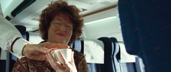 Movie still from “United 93” (2006), directed by Paul Greengrass – A woman sitting on top of an airplane holding a cup; Close Up shot, Over the shoulder angle