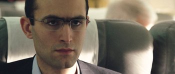 Movie still from “United 93” (2006), directed by Paul Greengrass – A person wearing glasses on a bus; Close Up shot, Low angle