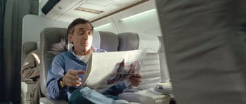 Movie still from “United 93” (2006), directed by Paul Greengrass – A man sitting on a plane reading a newspaper; Medium shot, High angle