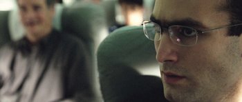 Movie still from “United 93” (2006), directed by Paul Greengrass – A person wearing glasses on a bus; Close Up shot, Low angle