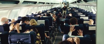 Movie still from “United 93” (2006), directed by Paul Greengrass – People are sitting on a plane and one is using a laptop; Wide shot, High angle