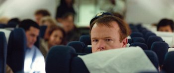 Movie still from “United 93” (2006), directed by Paul Greengrass – A man sitting in a seat on an airplane; Close Up shot, Over the shoulder angle