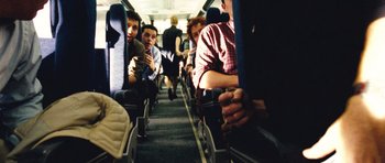 Movie still from “United 93” (2006), directed by Paul Greengrass – A group of people sitting on seats on an airplane; Wide shot, Overhead angle