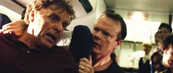 Movie still from “United 93” (2006), directed by Paul Greengrass – Two men on a train with one holding a microphone and the other holding a microphone; Close Up shot, Over the shoulder angle