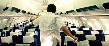 Movie still from “United 93” (2006), directed by Paul Greengrass – A man in a white dress shirt is on an airplane; Wide shot, High angle