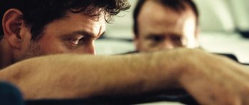 Movie still from “United 93” (2006), directed by Paul Greengrass – Two men sitting next to each other with their arms crossed; Extreme Close Up shot, Over the shoulder angle