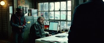 Movie still from “Unknown” (2011), directed by Jaume Collet-Serra – A man sitting in front of a computer at a desk; Medium shot, Over the shoulder angle