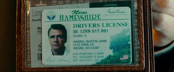Movie still from “Unknown” (2011), directed by Jaume Collet-Serra – A new hampshire driver's license is displayed on a table; Extreme Close Up shot, Overhead angle