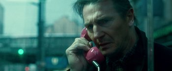 Movie still from “Unknown” (2011), directed by Jaume Collet-Serra – A man talking on a pink phone while sitting in a car; Close Up shot, High angle