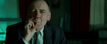 Movie still from “Unknown” (2011), directed by Jaume Collet-Serra – An older man in a suit smoking a cigarette; Close Up shot, Low angle