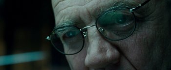 Movie still from “Unknown” (2011), directed by Jaume Collet-Serra – An older man wearing glasses and a beard; Extreme Close Up shot, Over the shoulder angle
