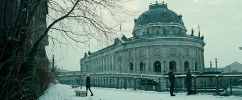 Movie still from “Unknown” (2011), directed by Jaume Collet-Serra – People walking in front of a large building on a snowy day; Extreme Wide shot, Low angle