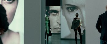 Movie still from “Unknown” (2011), directed by Jaume Collet-Serra – A woman standing in front of a large picture of a man; Extreme Close Up shot, Over the shoulder angle